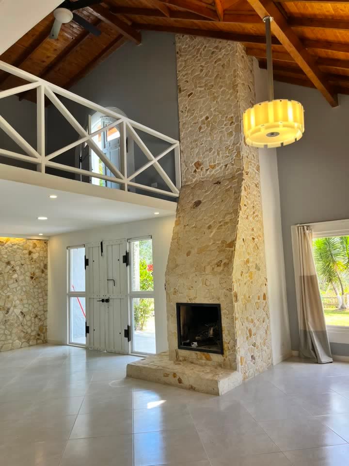 Sala de doble altura con chimenea en piedra y techo en madera